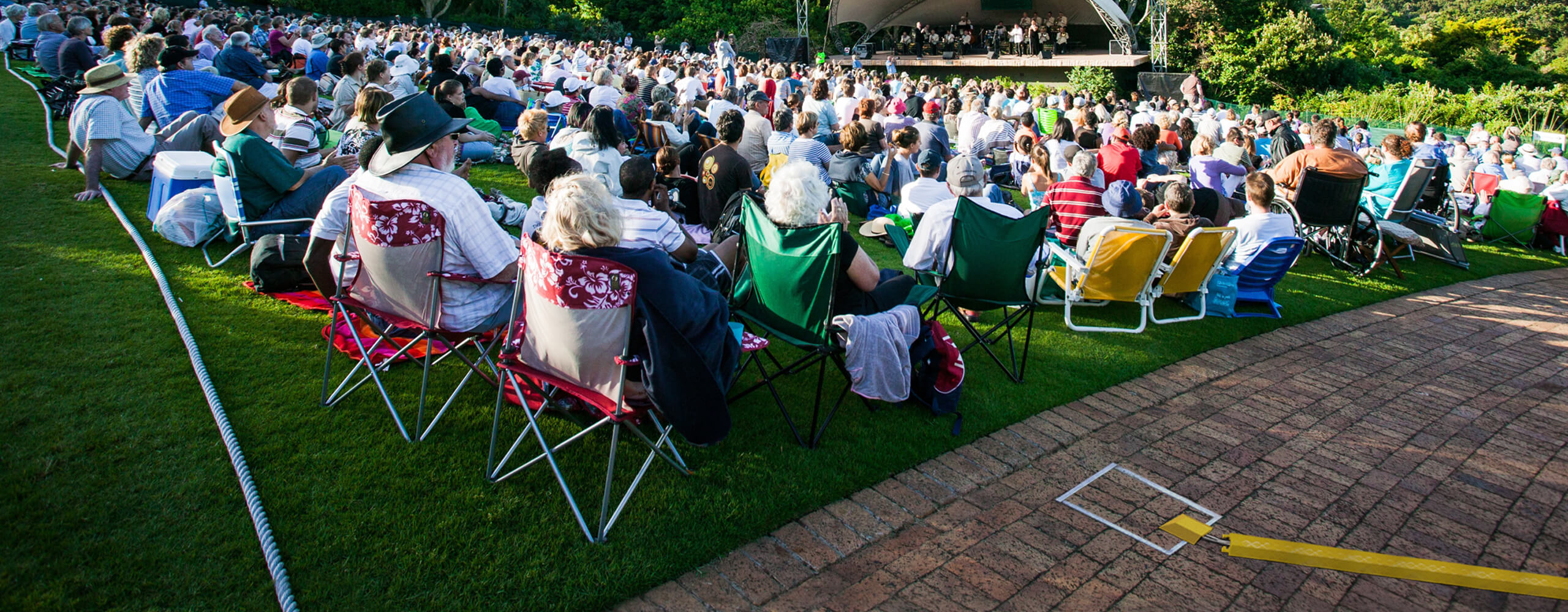 Image showing large seated crowd in front of an outdoor stage with closed in-ground unit in foreground.